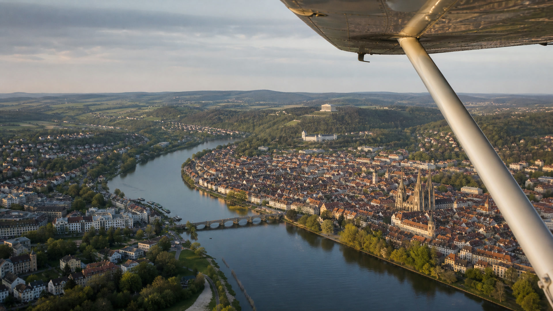 Luftaufnahme eines breiten Flusses mit historischer Stadt und Brücke