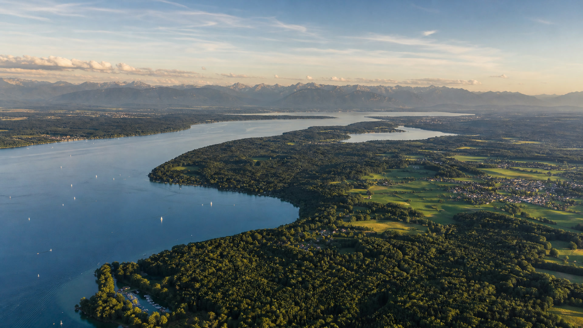 Luftaufnahme eines großen Sees mit bewaldeten Ufern und Segelbooten